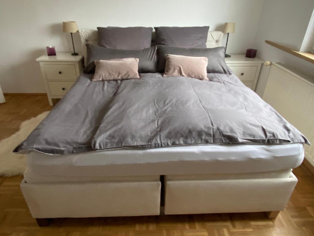 ein Bett mit grauer Bettwäsche und zwei rosa Kissen in der Unterkunft Findorff in Bremen