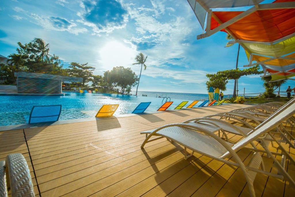 a wooden deck with chairs and a swimming pool at Maayo San Remigio in San Remigio