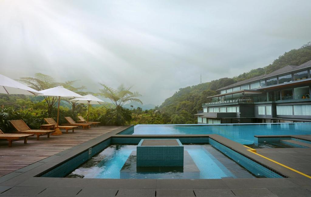 a pool at a hotel with tables and chairs at Forest Hills Hotel in Soreang