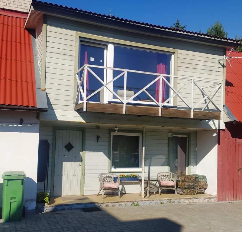uma casa com uma varanda com duas cadeiras e uma mesa em Saadjärve Kingu talu puhkemaja em Valgma