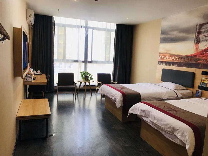 um quarto de hotel com duas camas e uma secretária em Thank Inn Chain Hotel henan zhengzhou xinzheng city north china road xuanyuan lake em Zhengzhou