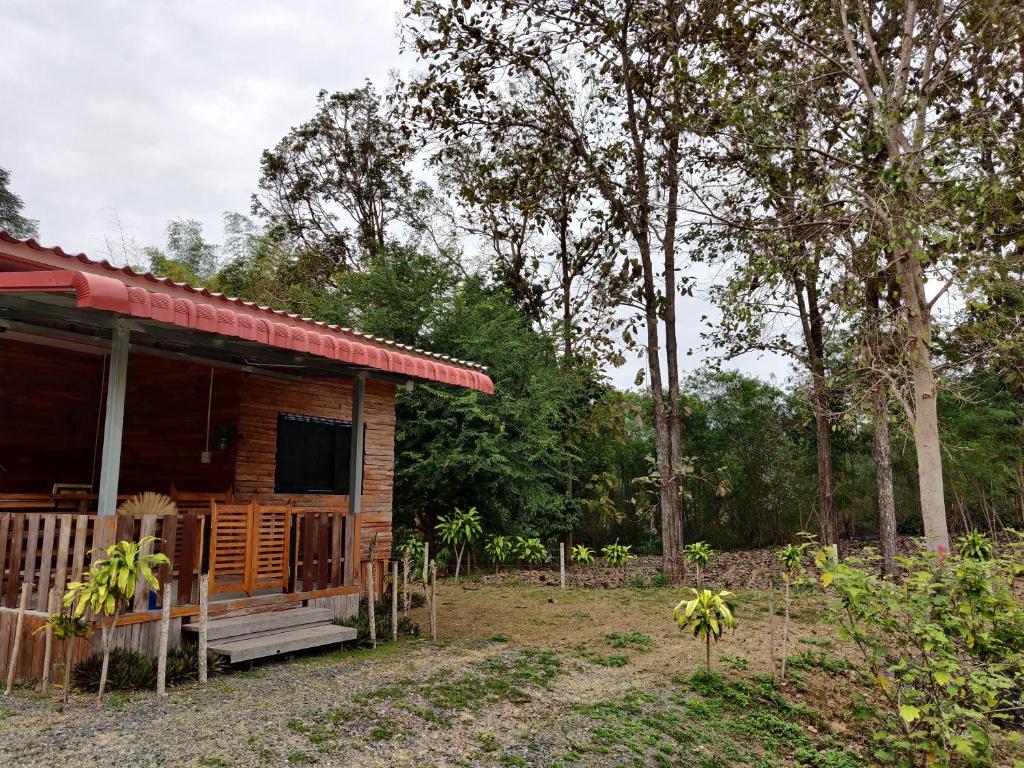 Cabaña de madera con porche y árboles en สายฝนการ์เด้น, en Ban On Luai