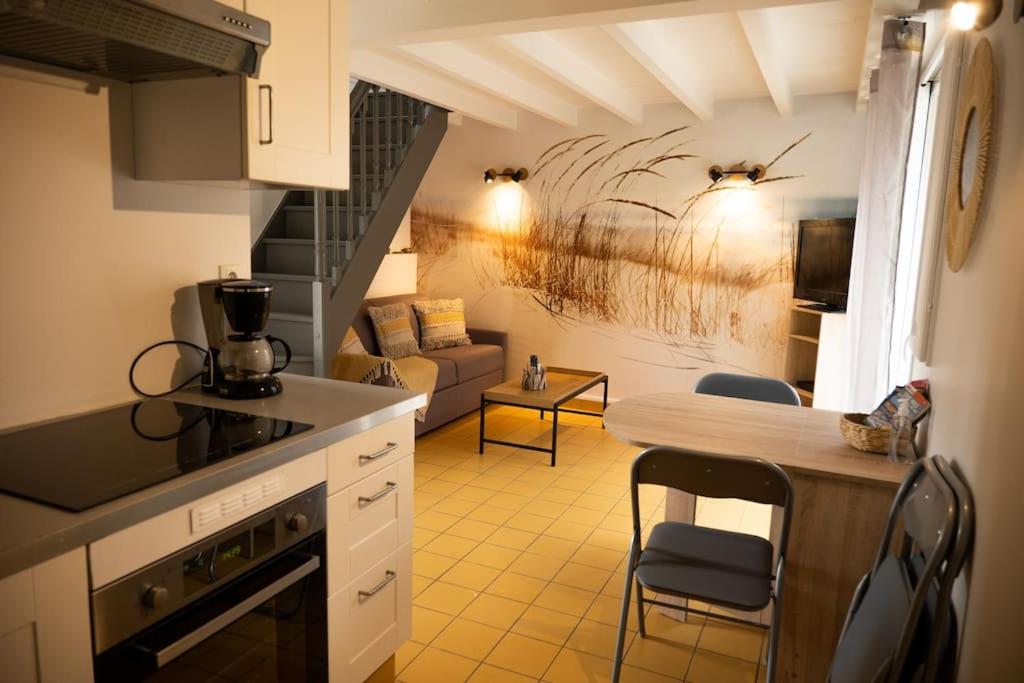 een keuken en een woonkamer met een tafel en stoelen bij Petite Maison située entre Saint-Malo et Cancale in Saint-Méloir-des-Ondes