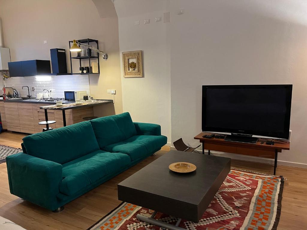 a living room with a green couch and a flat screen tv at HouSmart Senzanome 9/3 in Bologna