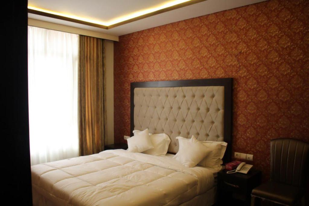 - une chambre avec un grand lit blanc et une fenêtre dans l'établissement Sadaf Hotel in Herat, à Hérat