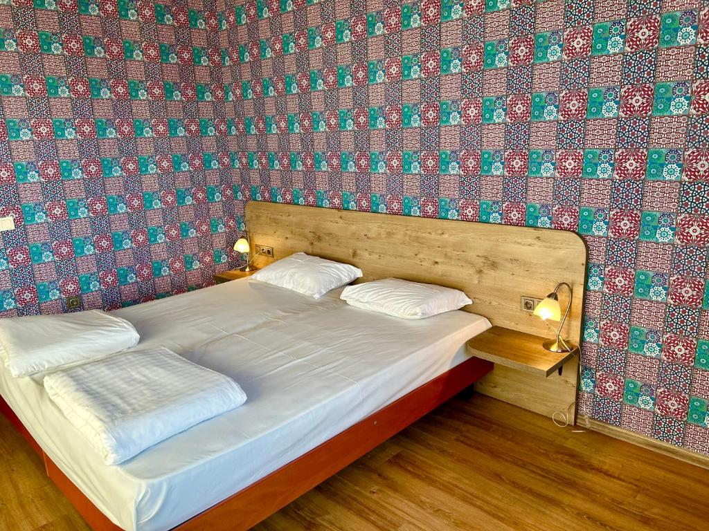 a bed in a room with a wall covered in wallpaper at Dragoman Hotel in Dragoman