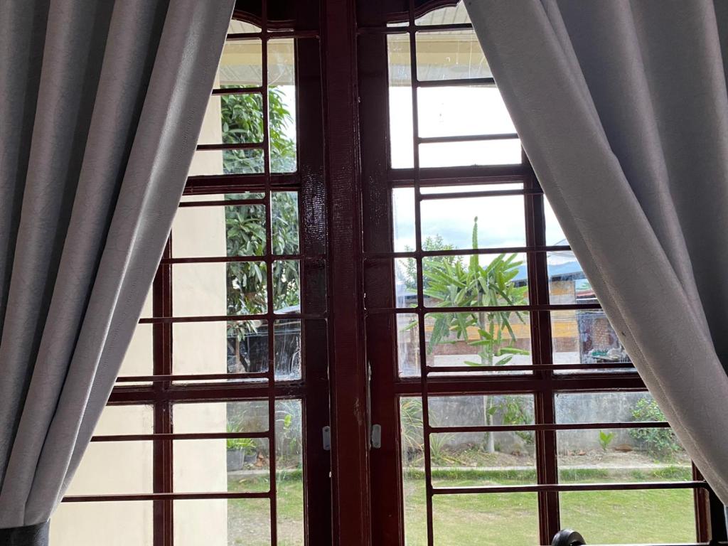 una ventana abierta con cortinas en una habitación en Paima Homestay, en Balige