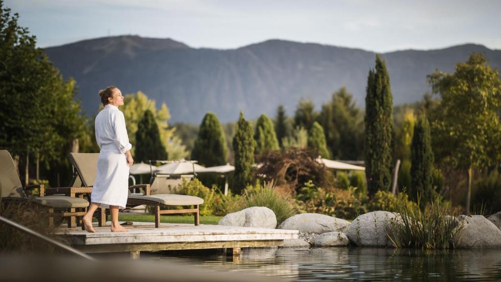 a woman standing on a dock near a body of water at Hotel Sonnenhof sun/spa/panorama in Falzes