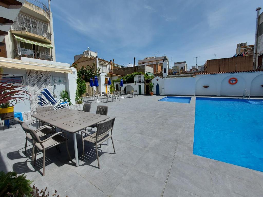 un patio con mesa y sillas junto a una piscina en Hotel Mediterrani Express, en Calella