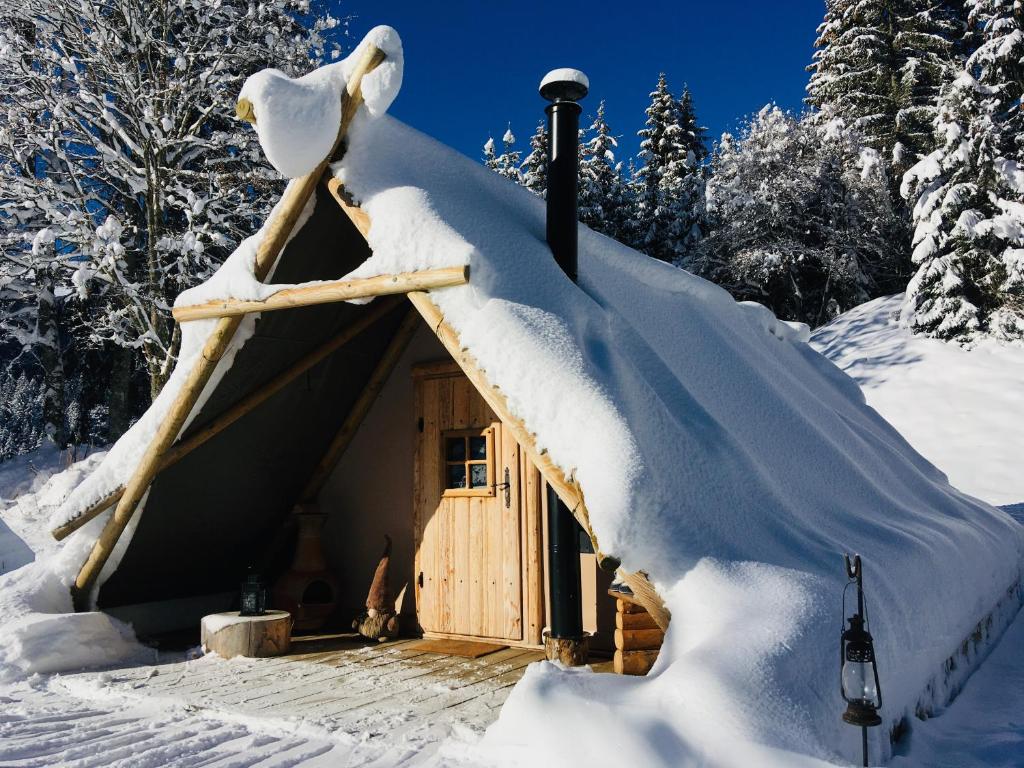 a cabin with a snow covered roof in the snow at Altipik - Lodges Insolites in Mont-Saxonnex