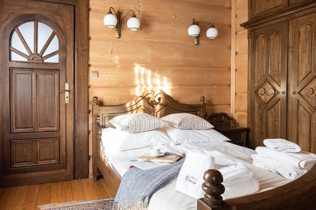 - une chambre dotée d'un lit avec des draps blancs et des murs en bois dans l'établissement Dom Crocus, à Zakopane