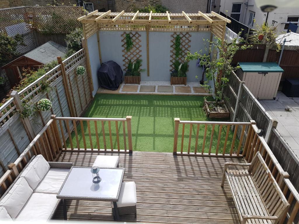 patio trasero con terraza de madera y mesa en Beautiful home in London, en Londres