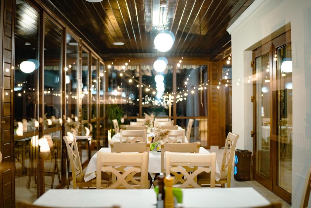 une salle à manger avec des tables, des chaises et des lustres blancs dans l'établissement Crama Jelna Resort & Spa, à Orheiu Bistriţei