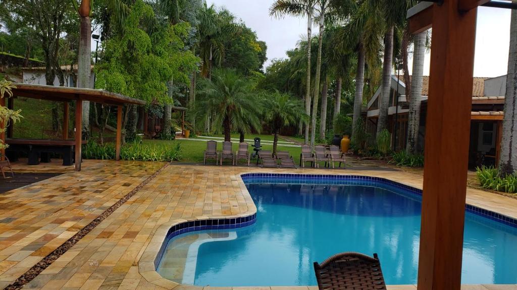 uma piscina num quintal com cadeiras e árvores em OYO Pousada e Hotel Putini em São Roque
