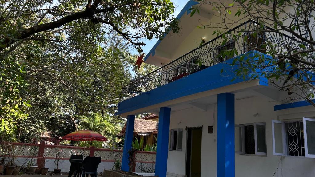 a blue and white house with a balcony at Muffys Guest House in Arpora