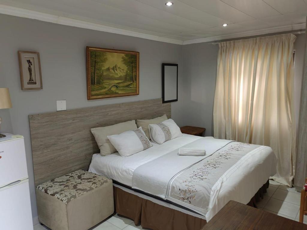 a bedroom with a large white bed and a window at Sibahlenomhlambi Guesthouse in Springs