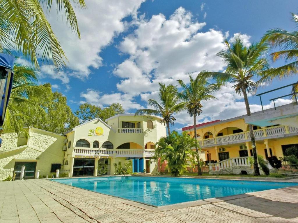una piscina frente a un edificio con palmeras en New Park Resort, en Mahajanga