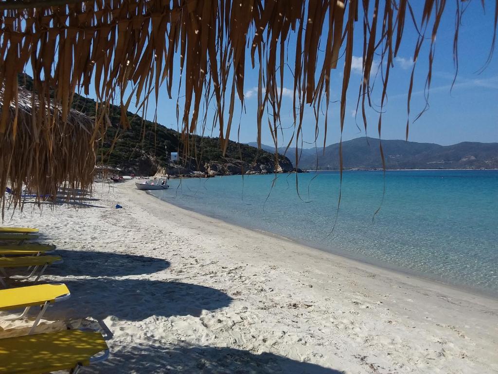 a beach with a straw umbrella and the water at Haus Despina in Sarti