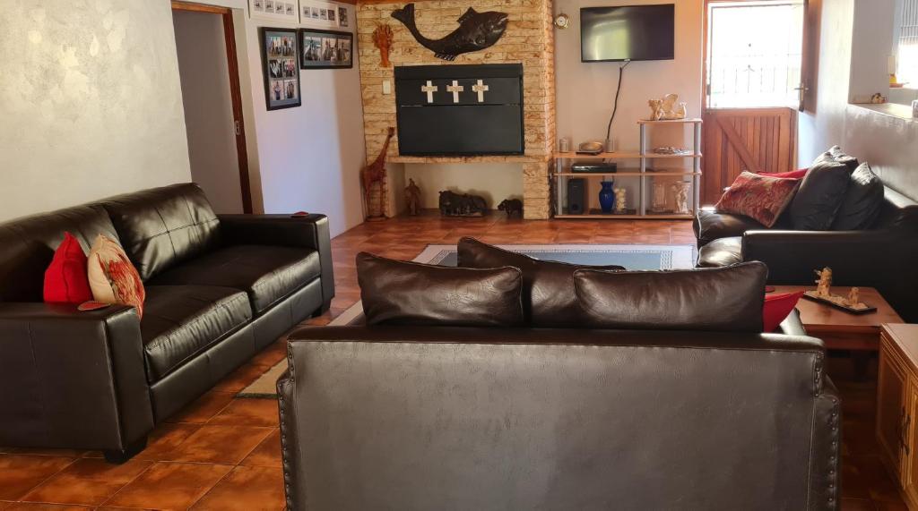 sala de estar con sofás de cuero y TV en Kleinbegin, 3 bedroom homely house, en Gansbaai