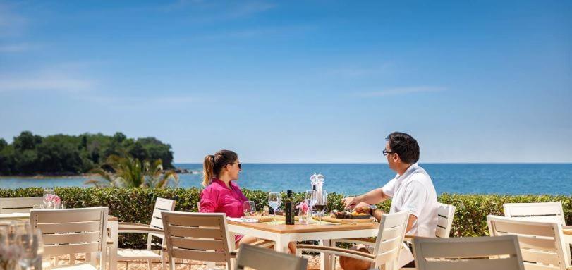 Un uomo e una donna seduti a un tavolo in spiaggia di Easyatent Safari tent Aminess Maravea a Novigrad Istria