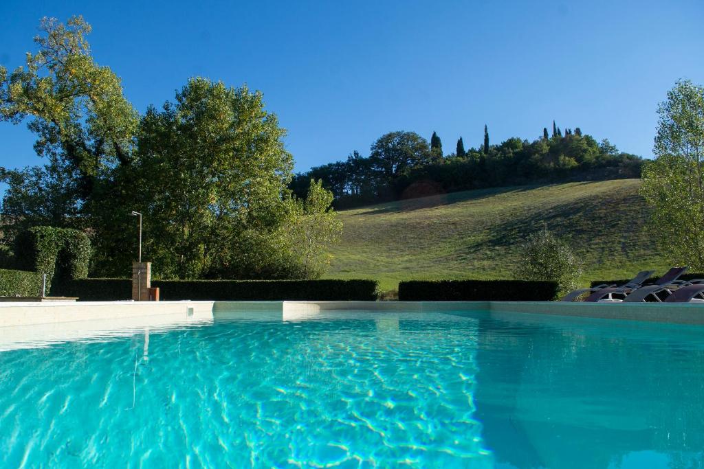 GhizzanoにあるTenuta di Ghizzano Resortの背景に丘があるスイミングプール(椅子付)