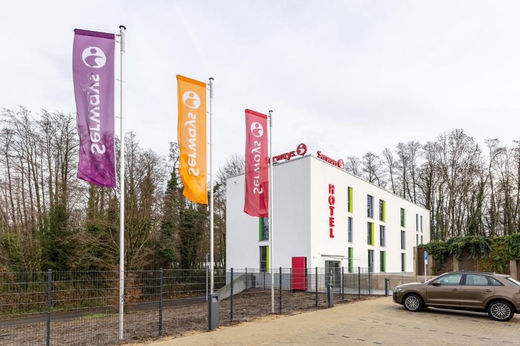 ein Auto, das vor einem Gebäude mit Bannern parkt in der Unterkunft Serways Hotel Hösel in Ratingen