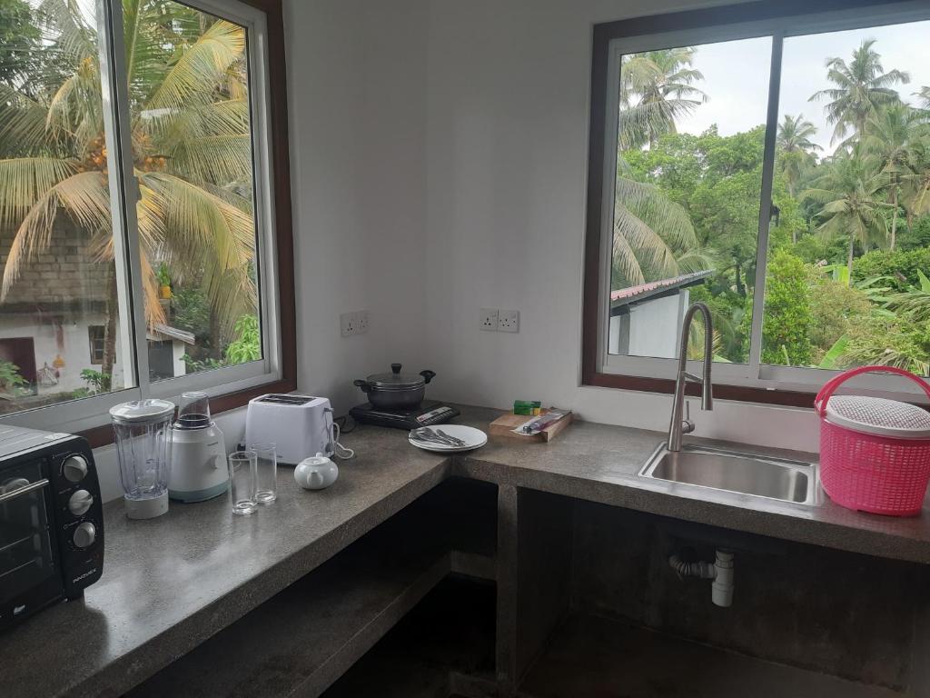 a kitchen counter with a sink and two windows at Hotel Paradiso, in Unawatuna