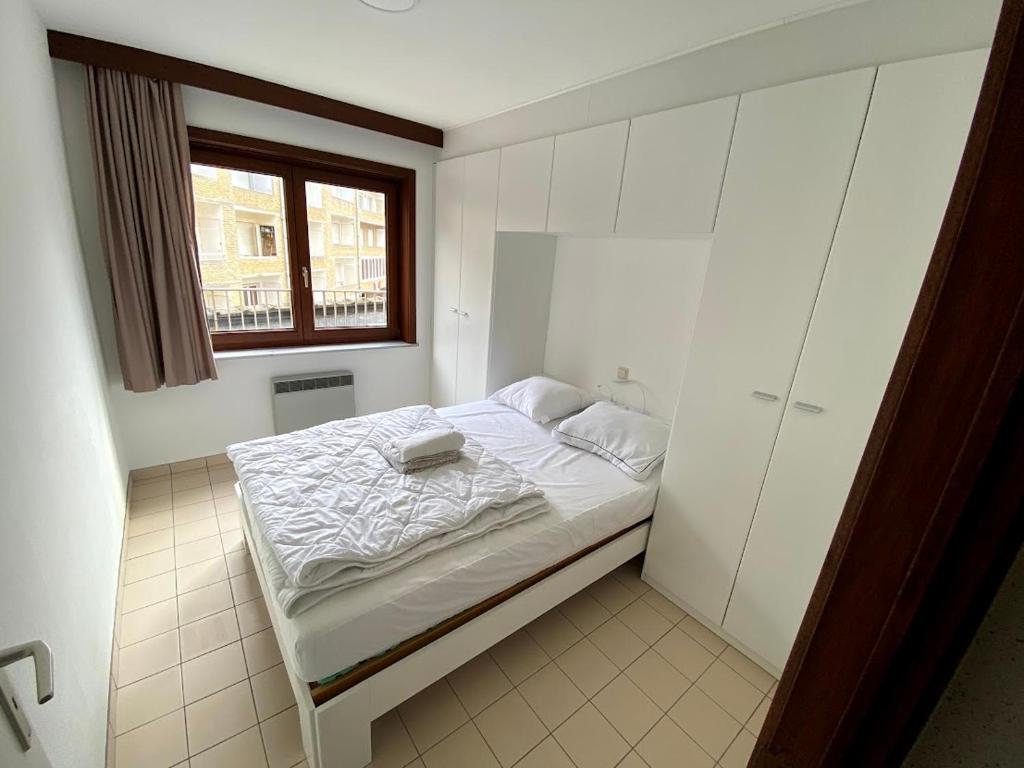 a small bedroom with a bed and a window at Appart sympa 6p avec garage et terrasse ensoleillée et spacieuse à 25m de la Mer Westende in Middelkerke