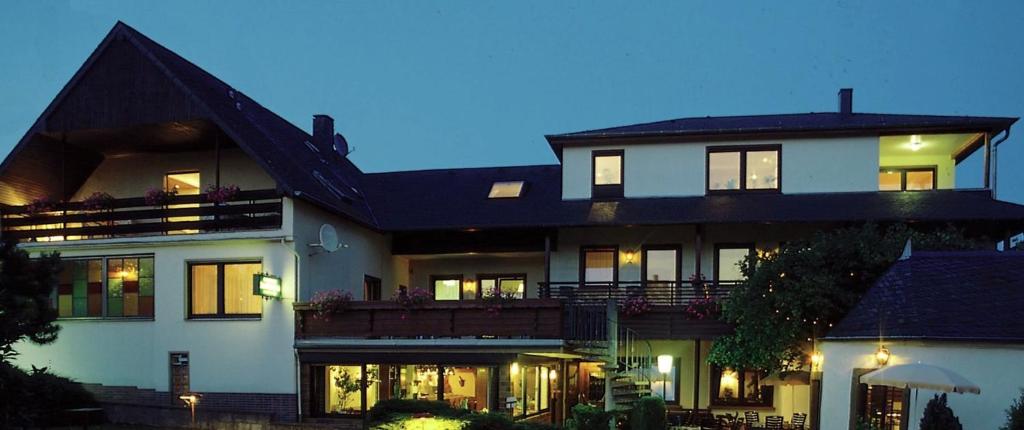 ein großes weißes Haus mit eingeschaltetem Licht in der Unterkunft Pension Zum Golfstübchen in Echternacherbrück