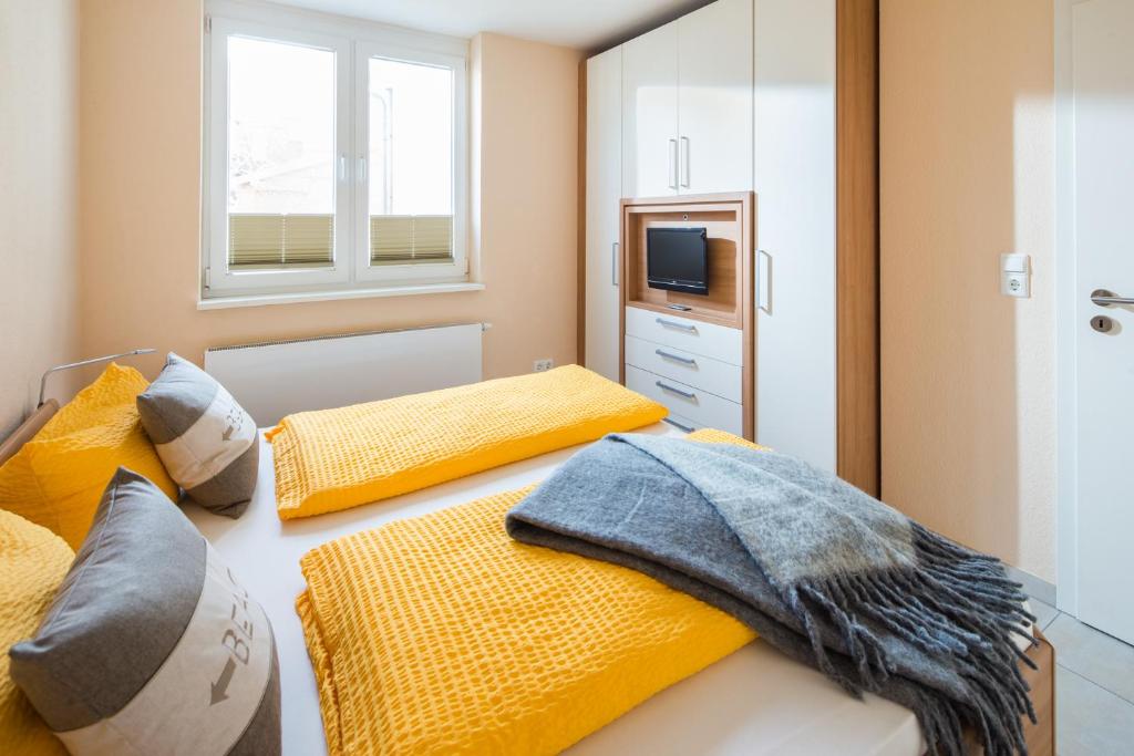 sypialnia z 2 łóżkami i żółtymi poduszkami w obiekcie Michels Haus Kleine Auszeit w mieście Norderney