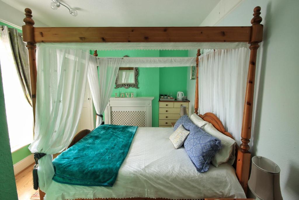 a bedroom with a canopy bed with a blue blanket at Beaches Guesthouse in Paignton