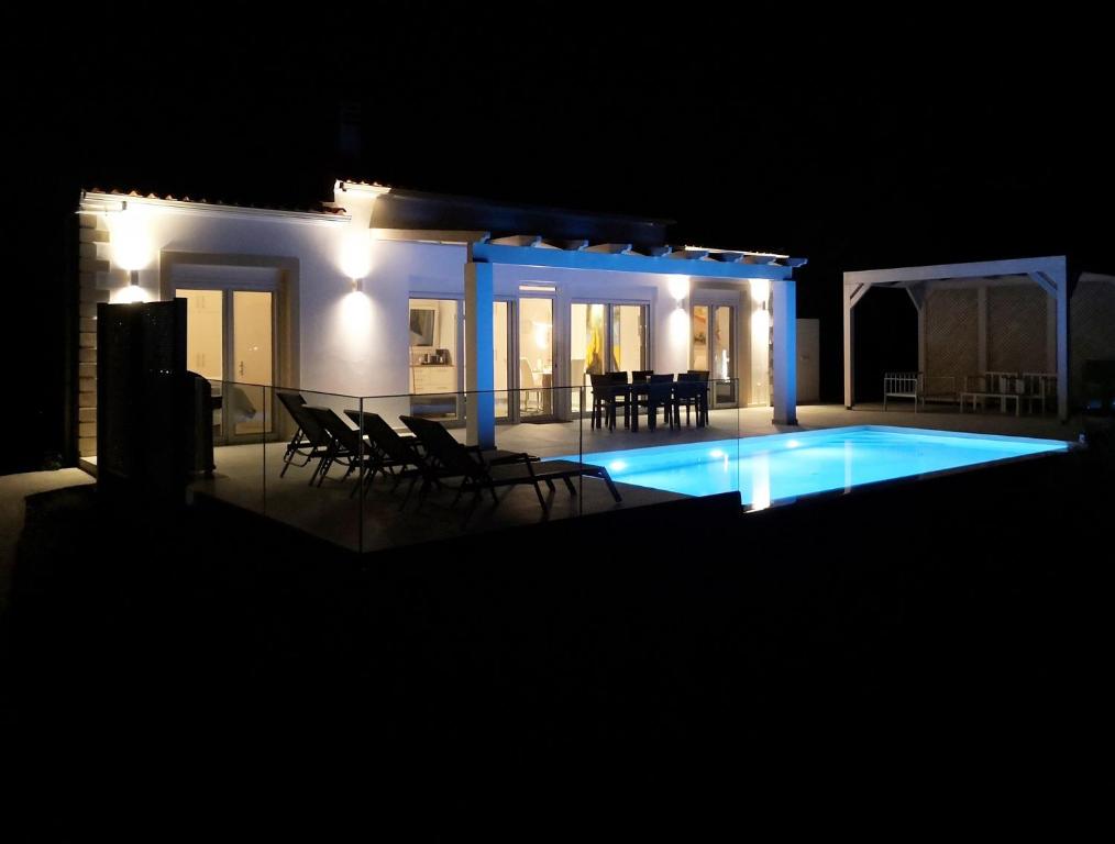 a swimming pool at night with chairs around it at Sunset Sea View Villa 10 in Afionas