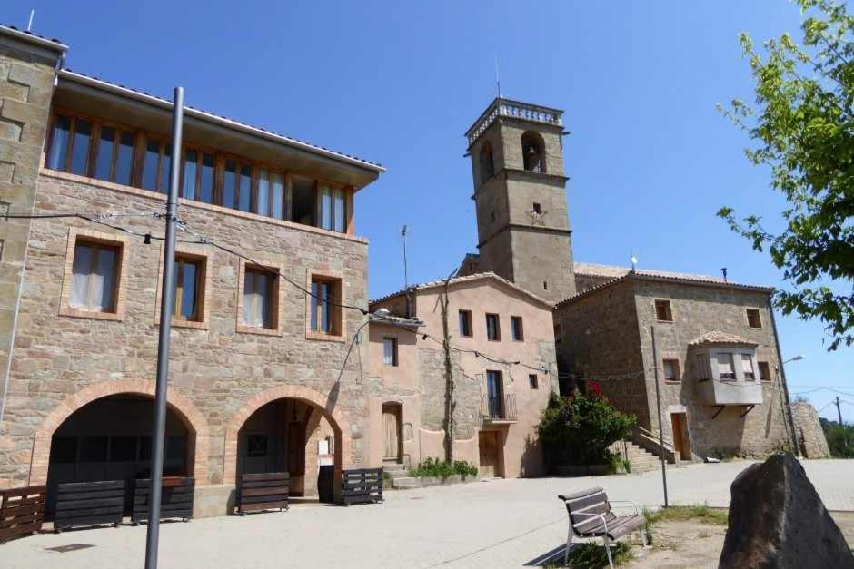 un edificio con una torre de reloj y un edificio con un banco en Cal Moliner De Castelladral, en Castelladral