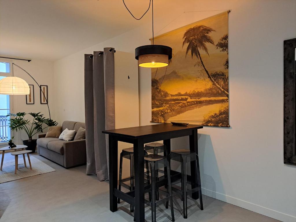 ein Wohnzimmer mit einem Tisch und einem Gemälde an der Wand in der Unterkunft Grand Studio Luxe in Sète