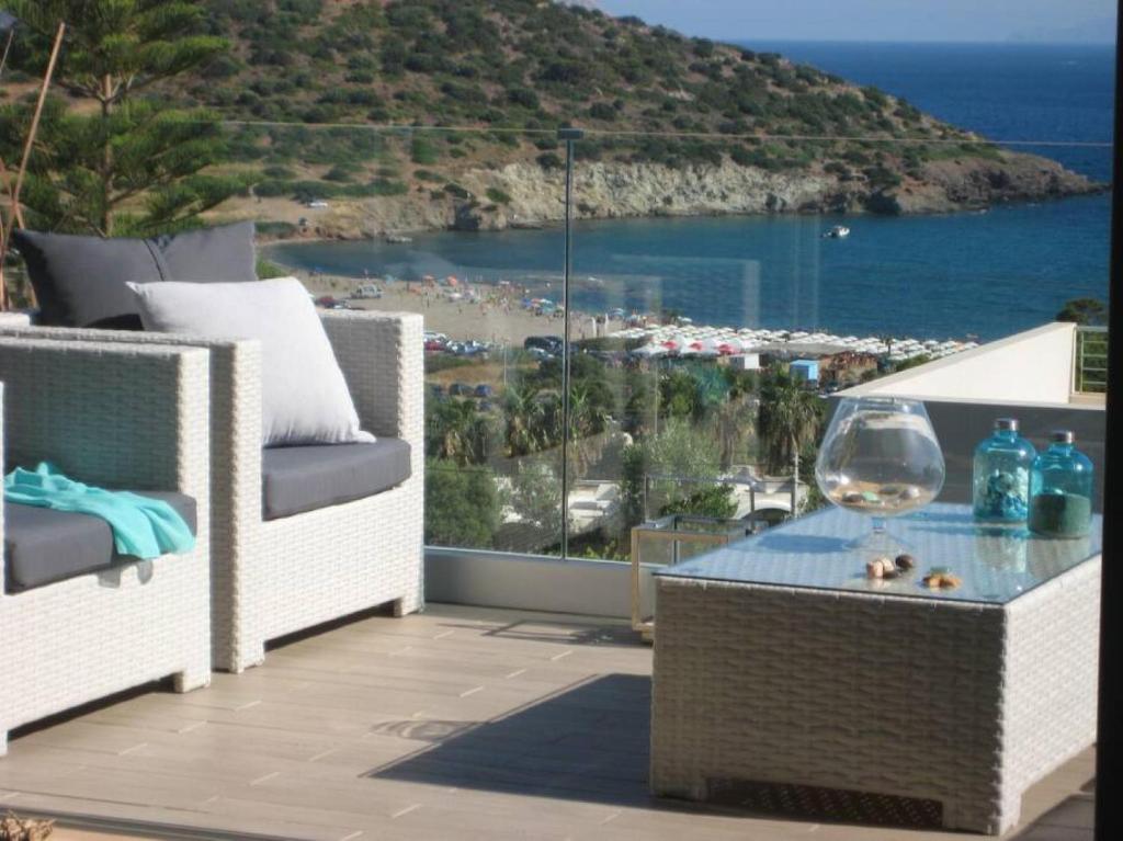 a balcony with a glass table and chairs and the ocean at villa in Agios Nikolaos Anavyssos in Áyios Yeóryios