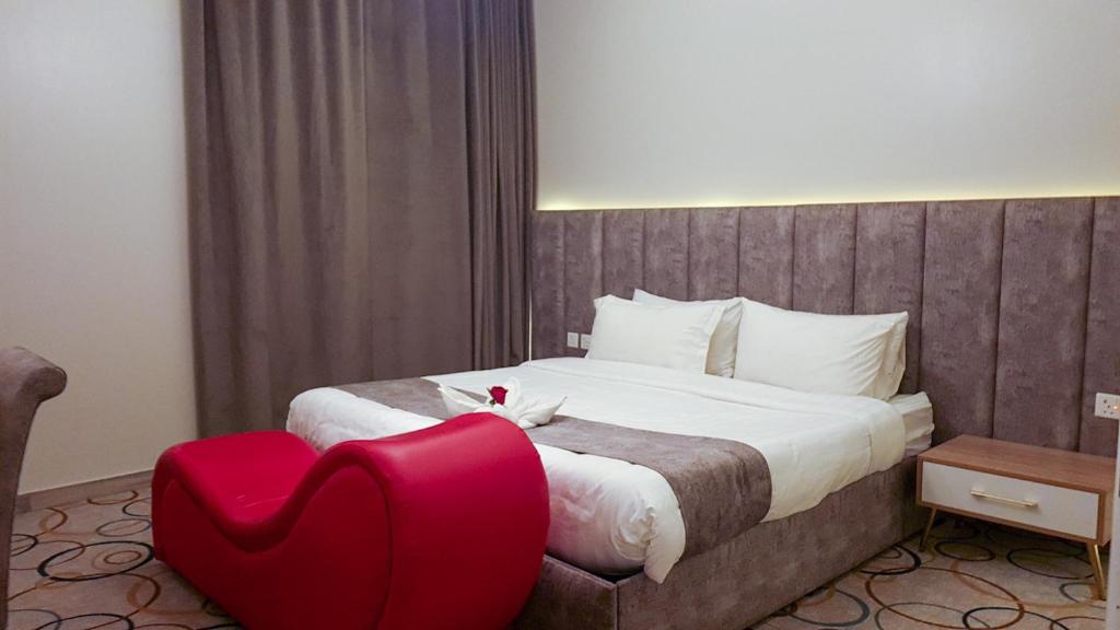 een slaapkamer met een groot bed en een rode stoel bij جولدن أبها المضياف in Abha