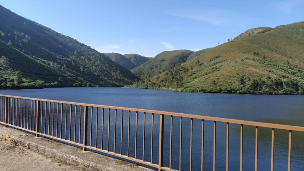 un puente sobre un lago con montañas en el fondo en CASA RURAL LA TORRITA, en Acebo