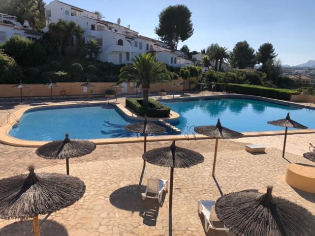 une grande piscine avec des parasols et des chaises dans l'établissement Casita Mona - Attractive Studio Apartment 4kms from the beach, à Moraira