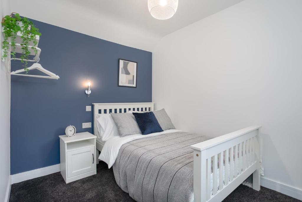 1 dormitorio con cama blanca y pared azul en Central Avenue Apartment, en Belfast