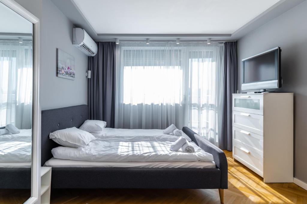 een slaapkamer met een bed, een tv en een dressoir bij Cosy 1BD Flat with a Lovely Balcony in Sofia