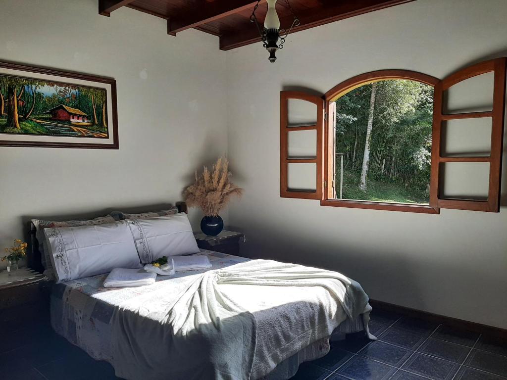 Un dormitorio con una cama y una ventana abierta. en Fazendinha Paraíso, en Lumiar