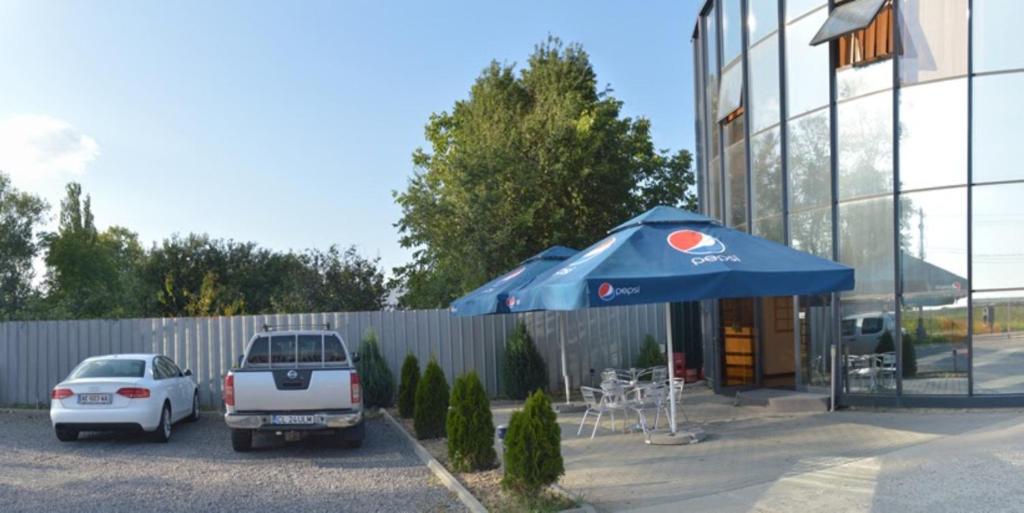 dos autos estacionados en un estacionamiento al lado de un edificio en Motel Alexander, en Olteniţa