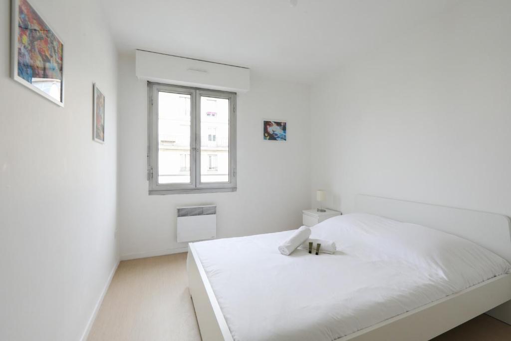 um quarto branco com uma cama e uma janela em Spacious and calm apartment in Montrouge - Welkeys em Montrouge