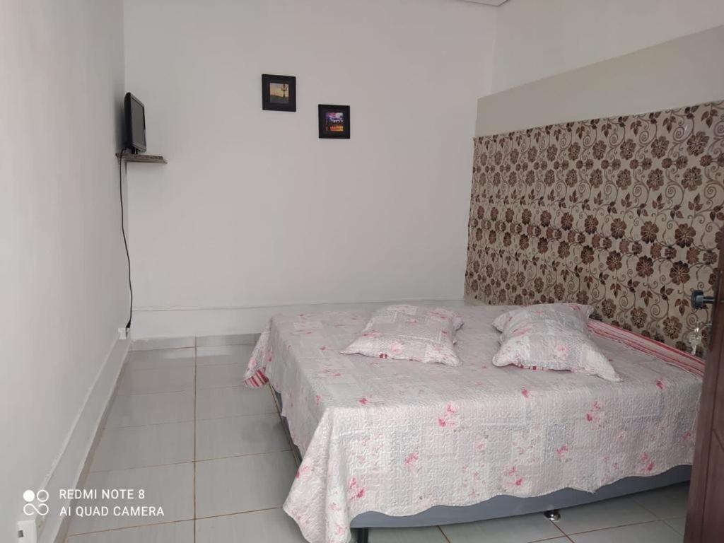 um quarto com uma cama com duas almofadas em Pousada Flor da Chapada em Chapada dos Guimarães