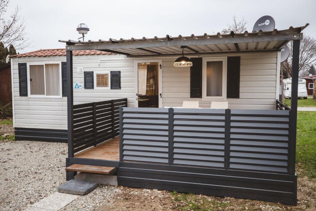 ein winziges Haus mit einem schwarzen Zaun davor in der Unterkunft Holiday cottage II with 2 Thermal Riviera Tickets in Moravske-Toplice