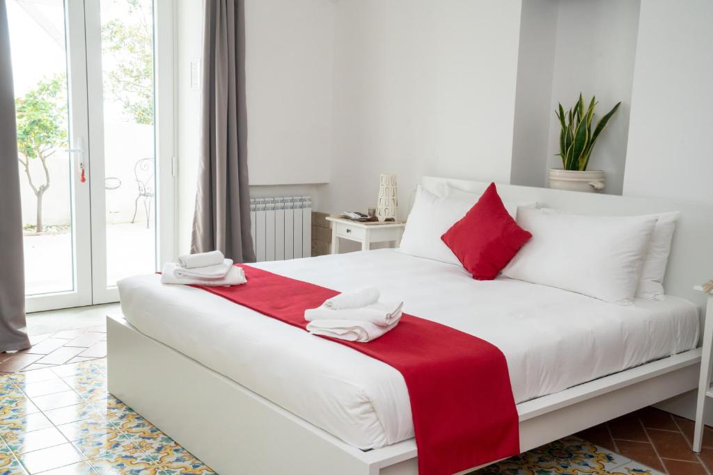 Una cama blanca con almohadas rojas y blancas. en Le Stanze di Sissi - Luxury Suites, en Nápoles
