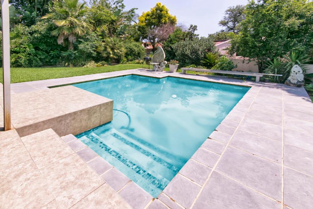 Modern 4 bedroom residential villa with pool, fully solar powered في Sandton: مسبح بمياه زرقاء في حديقة خلفية