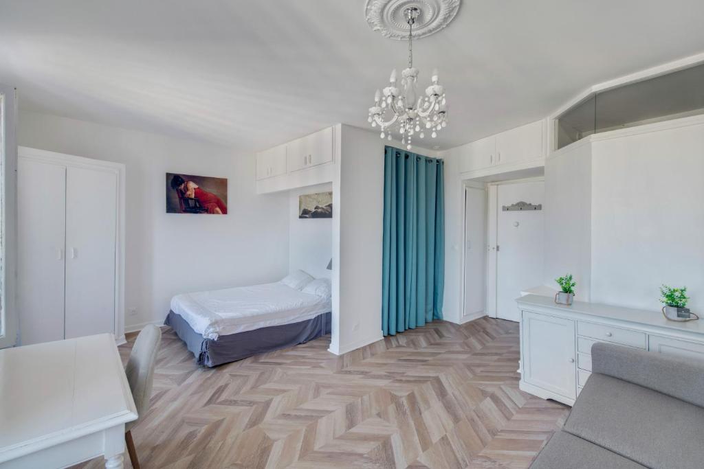 een slaapkamer met een bed en een kroonluchter bij Le Milady- Versailles in Versailles