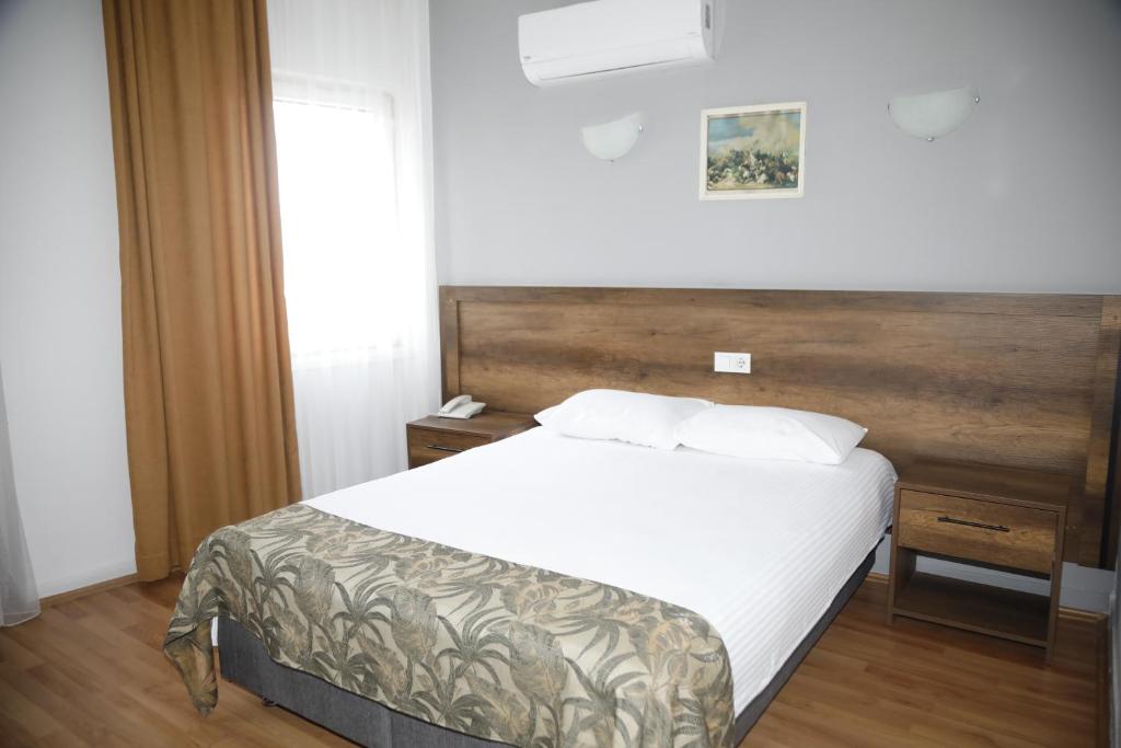 a bedroom with a white bed with a wooden headboard at Cihan Palas in Ankara