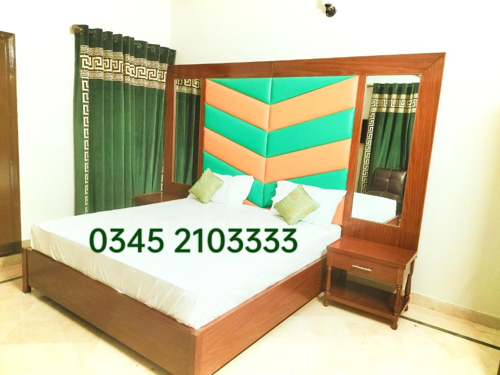 a bedroom with a bed with a wooden frame and a mirror at Subhan Palace Guest House in Karachi